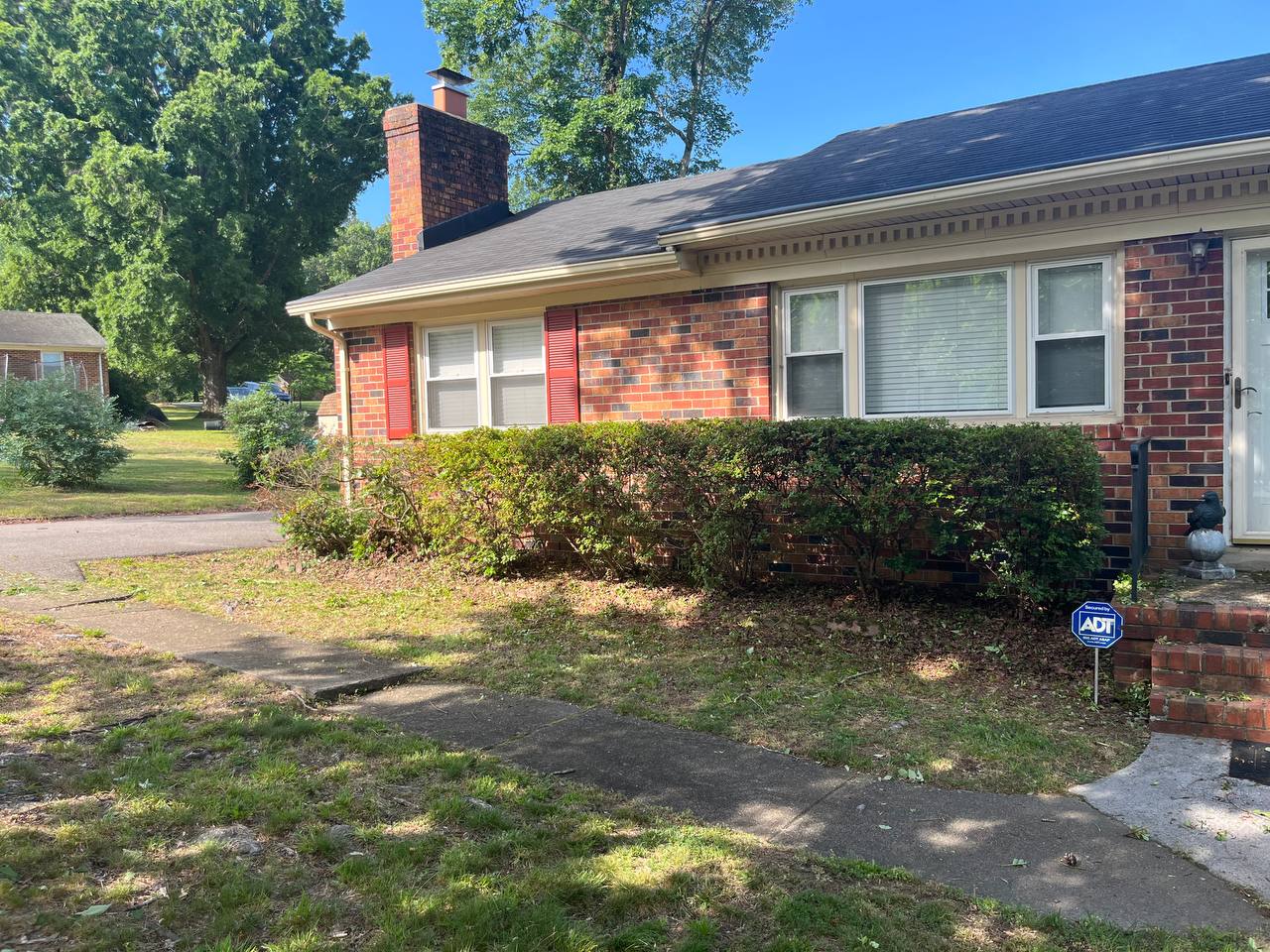 Brick home with shrubs neatly trimmed after Capitol City Lawncare service